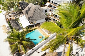 Un resort con piscina, palmeras y un edificio de techo de paja.