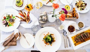 Una mesa servida con diversos platos, incluyendo un bistec, ensalada y pan, sugiriendo un ambiente para comer.