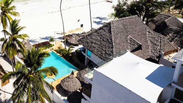 A beach resort with a pool, palm trees, and a view of the ocean. - Alladin Boutique Beach Hotel And Spa Zanzibar (Matemwe)