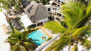 A resort with a swimming pool, palm trees, and a thatched-roof building. - Alladin Boutique Beach Hotel And Spa Zanzibar (Matemwe)