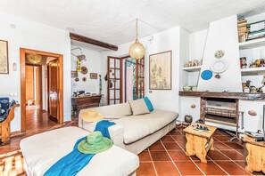 Ein Wohnzimmer mit Sofa, einem Holztisch, einer Pendelleuchte und einem Kamin.