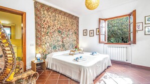 A bedroom with a bed, a window with a view, a hanging light fixture, and a patterned wall. - Lu Maggiu, Santa Teresa di Gallura, Italy (Santa Teresa di Gallura)
