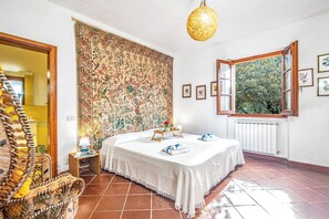 Une chambre à coucher avec un lit, une fenêtre donnant sur un beau paysage, un luminaire suspendu et un mur décoré de motifs.