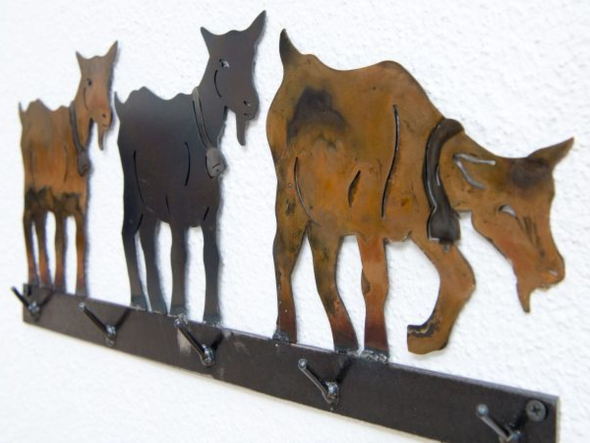 Una escultura metálica en la pared que representa tres vacas.