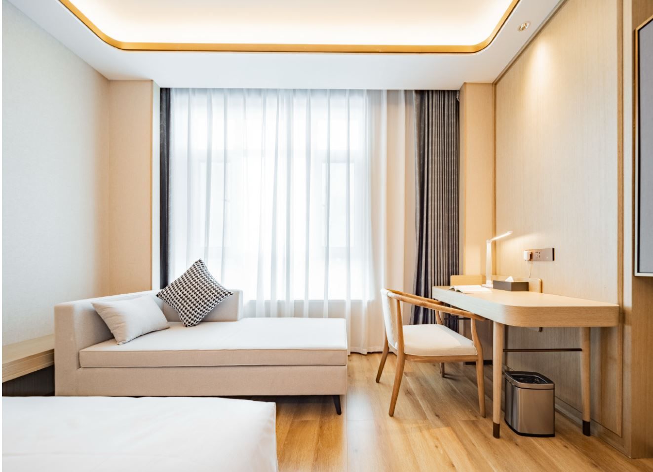 A modern hotel room with a sofa, a desk, and a chair.