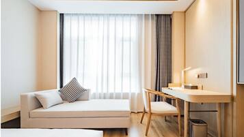 A modern hotel room with a sofa, a desk, and a chair.