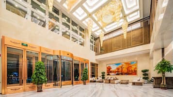 A spacious lobby with a high ceiling, large windows, and a central seating area.