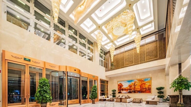 A spacious lobby with a high ceiling, large windows, and a central seating area.