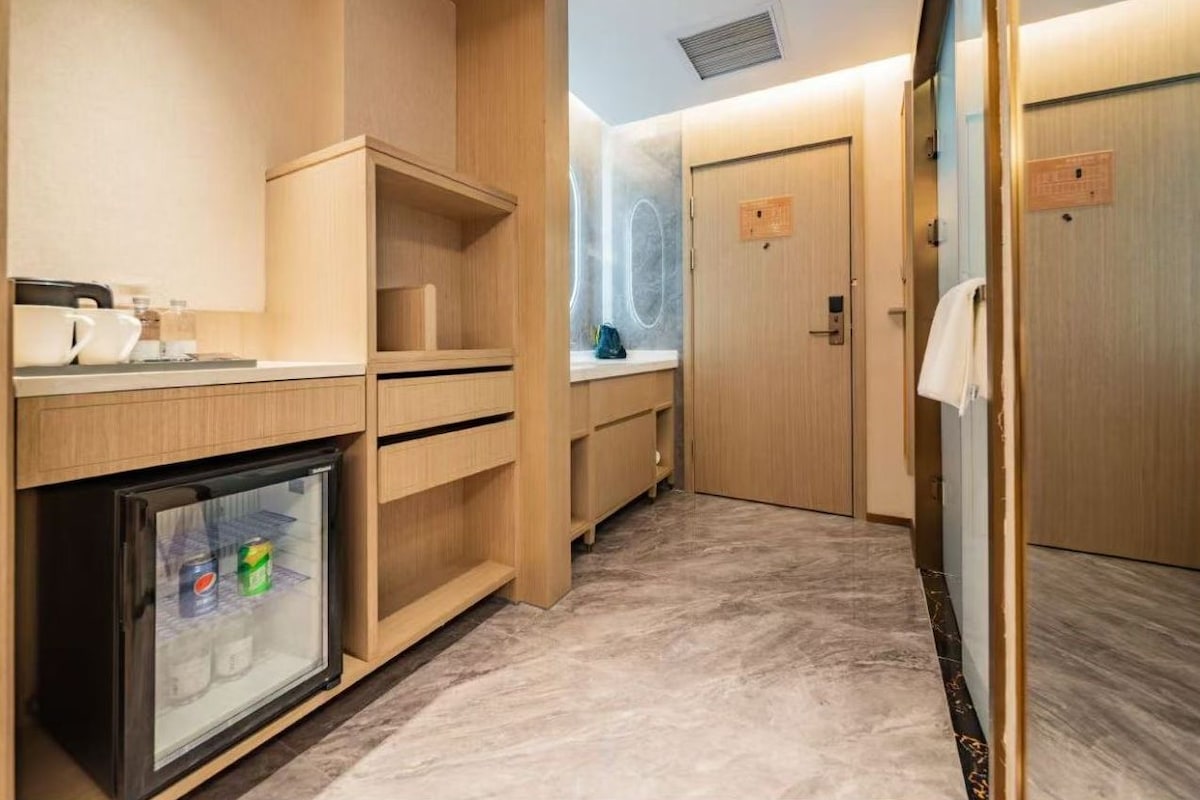 Una habitación de hotel compacta con kitchenette, un mini refrigerador y una zona de ducha.