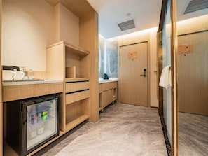 Una habitación de hotel compacta con kitchenette, un mini refrigerador y una zona de ducha.