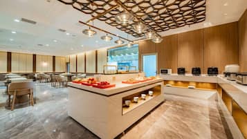 A modern hotel lobby with a central island, seating area, and a kitchen counter.