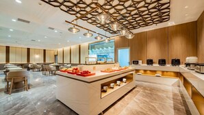 A modern hotel lobby with a central island, seating area, and a kitchen counter.