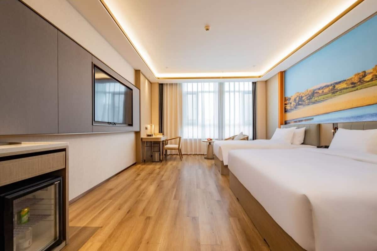 Habitación de hotel con cama, escritorio, televisión y ventana con vistas.