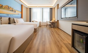 Habitación de hotel con dos camas, un escritorio, una silla, un televisor y un minibar.