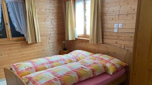 En stuga med träpanel, ett rum med en säng, gardiner och ett fönster.