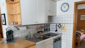 Ett kompakt kök med diskho, spis och träskåp.