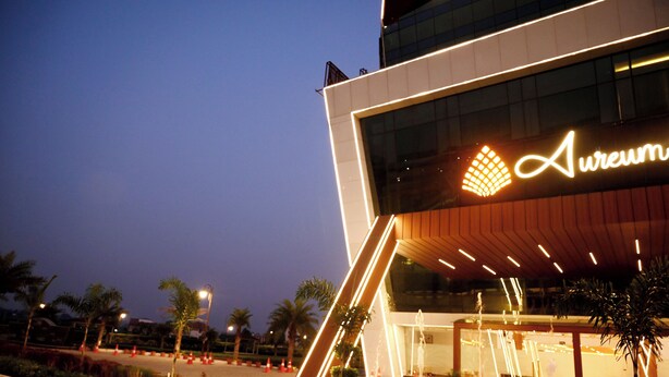 A modern building with a prominent illuminated sign reading 'Aureum.' - Aureum Grand Hotels & Resorts (Pathankot)