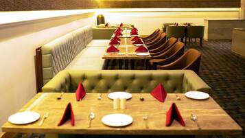 A restaurant with a long table set for multiple guests, cushioned seating, and a carpeted floor.
