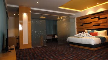 A modern hotel room with a bed, a desk, and a seating area.