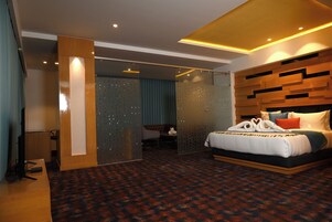 A modern hotel room with a bed, a desk, and a seating area.