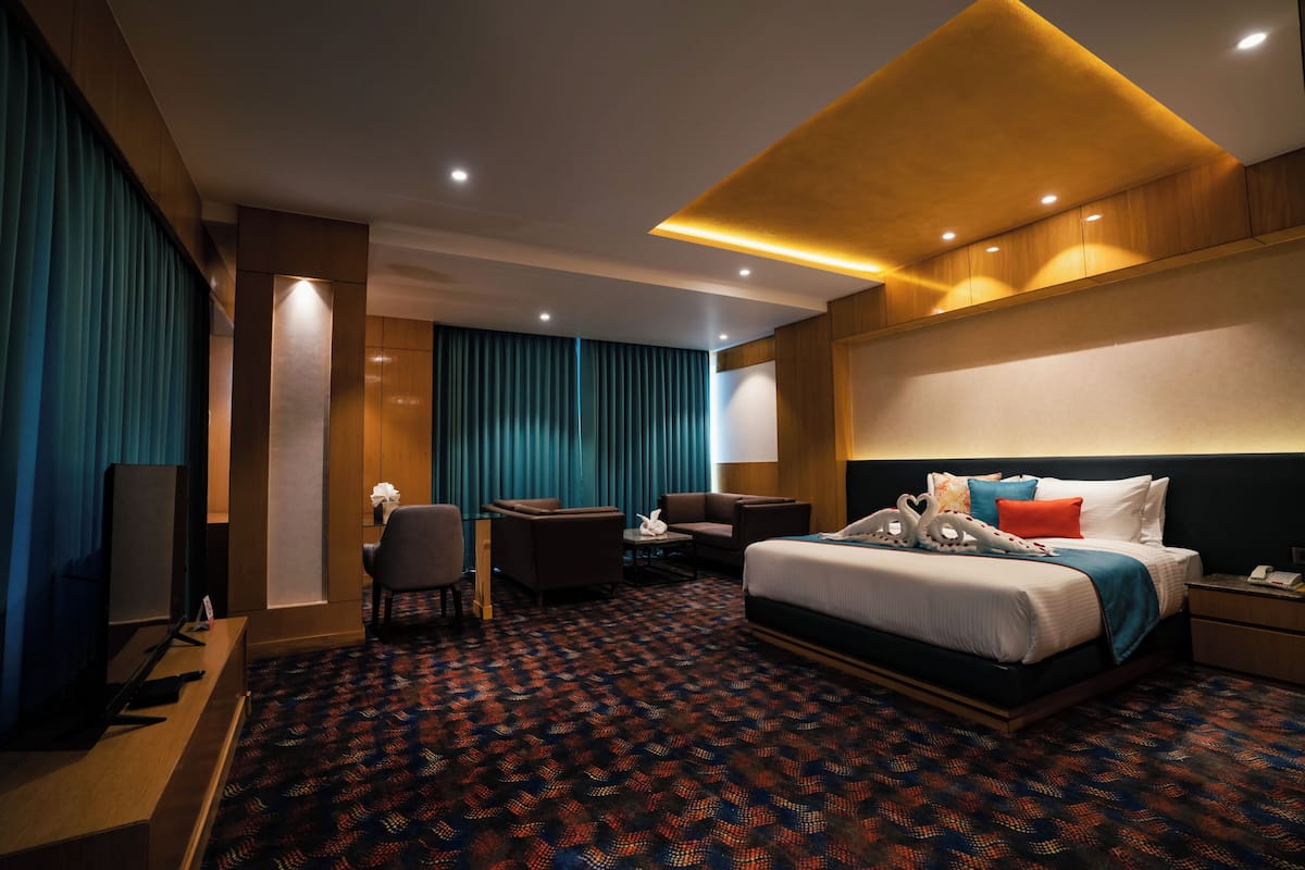 A hotel room with a bed, desk, chair, and a TV.