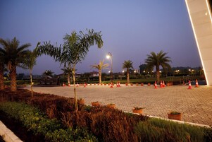 Una zona pavimentada con palmeras, plantas en macetas y conos de tráfico naranjas.