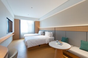 A hotel room with two beds, a round table, a sofa, a TV, and a window with curtains. - Ji Hotel Changchun Silicon Valley Street Party Sch (Changchun)