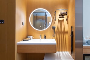 A modern bathroom with a wooden vanity, a round mirror, a handheld showerhead, and a towel rack. - Ji Hotel Changchun Silicon Valley Street Party Sch (Changchun)