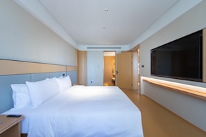 A hotel room with a large bed, a TV mounted on the wall, and a wooden headboard. - Ji Hotel Changchun Silicon Valley Street Party Sch (Changchun)