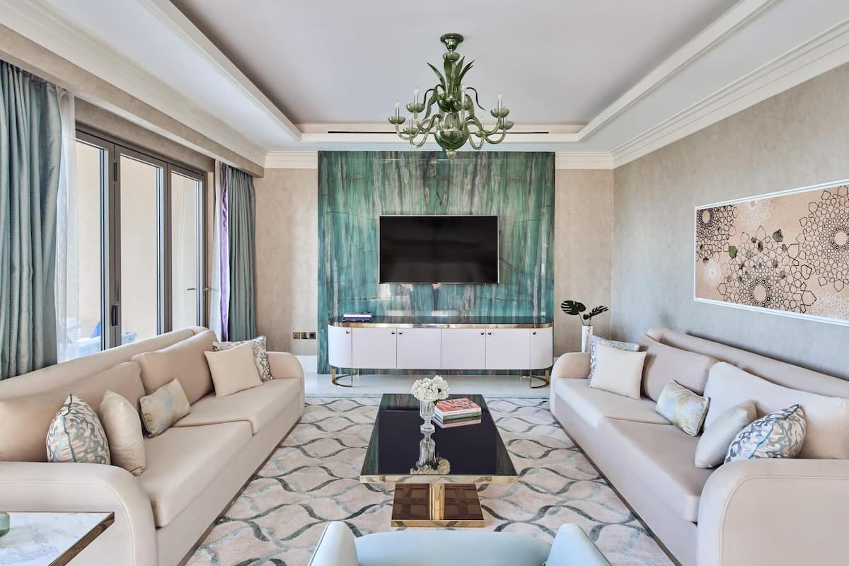 A spacious living room with a large TV, two sofas, a coffee table, and a chandelier.
