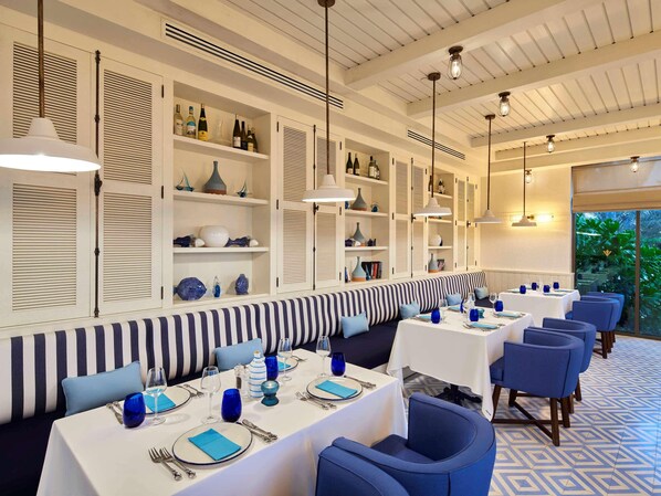 A restaurant with striped seating, white tables, and blue accents.