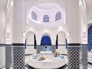 A spacious lobby with a central fountain, white walls, and blue patterned columns.
