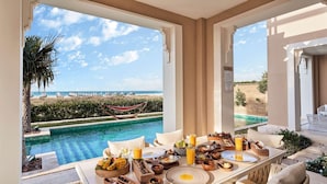 A dining area with a pool view, outdoor seating, and a buffet setup. - Club Prive By Rixos Saadiyat (Abu Dhabi)
