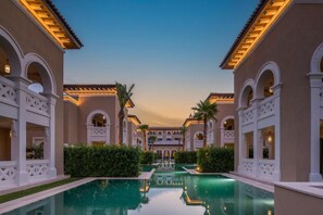 A pool surrounded by buildings with arched windows and balconies, reflecting in the water.