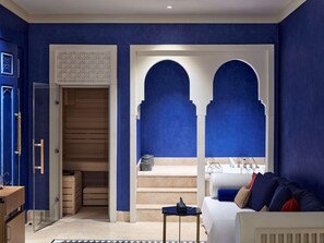 A room with blue walls, a wooden door, a staircase, and a bed with pillows. - Club Prive By Rixos Saadiyat (Abu Dhabi)