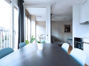 Une cuisine moderne avec un coin repas, une grande fenêtre et une plante sur la table.