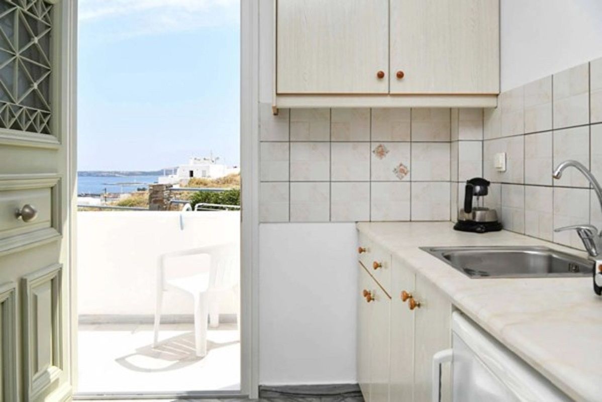 Una cocina con vista al mar, un lavabo y una silla afuera.