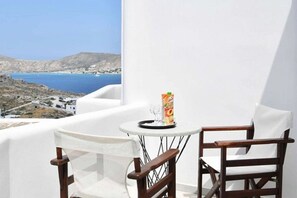 A balcony with a table and two chairs, overlooking a coastal landscape. - Hara Studios (Paros)