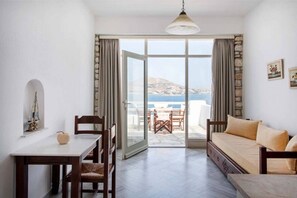 Una habitación con una mesa de comedor, sillas, un sofá y vistas al mar a través de un ventanal.