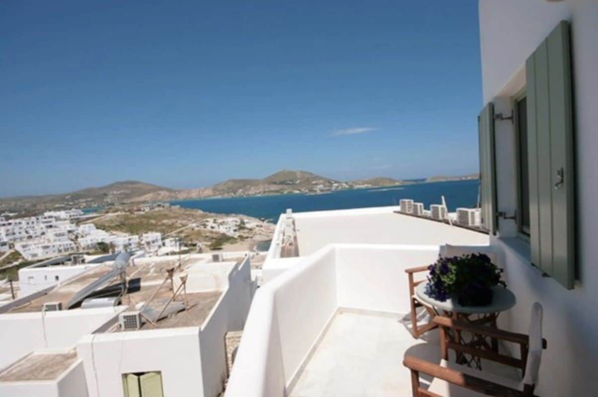 A balcony with a view of the sea and white buildings.