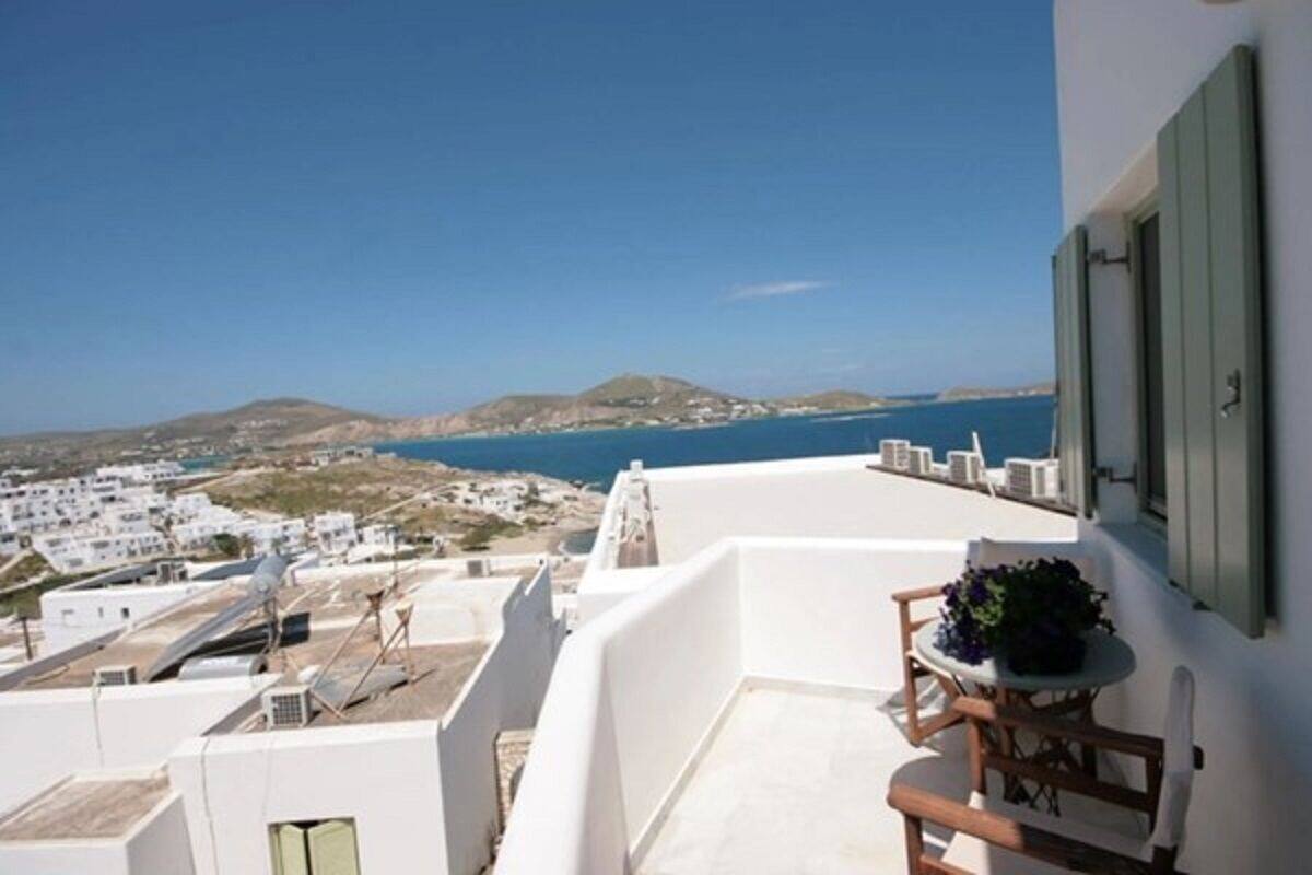 A balcony with a view of the sea and white buildings.