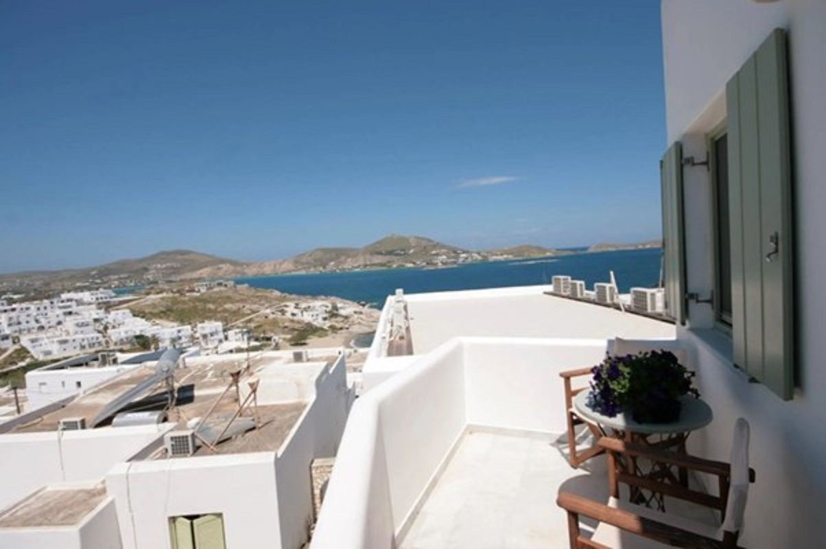 A balcony with a view of the sea and white buildings.