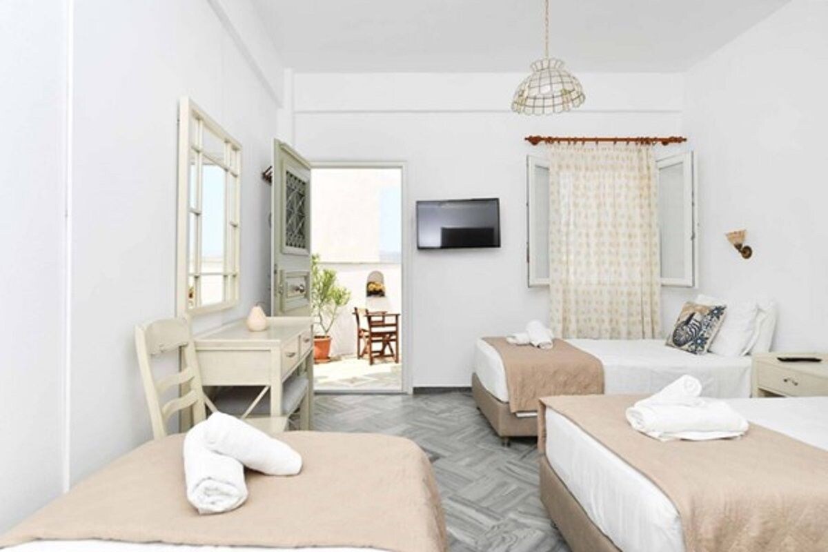 Habitación de hotel con dos camas, un escritorio, una silla, un televisor y un ventanal con cortinas.