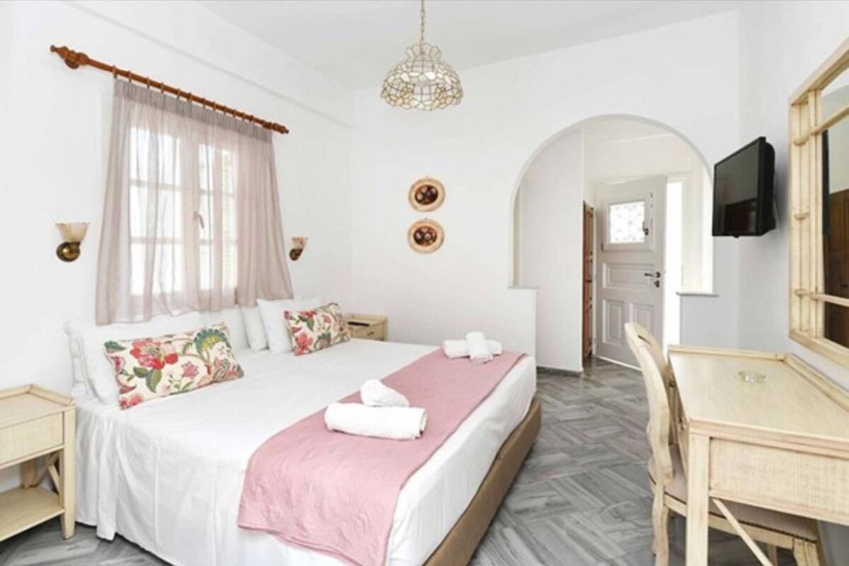 Een hotelkamer met een bed, een bureau, een televisietoestel en een kroonluchter.