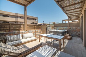 An outdoor patio area with a sofa, table, and hot tub. - Senseana Seaside Resort And Aquadventure (Analipsis)
