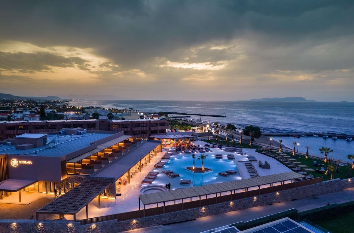 A resort with a swimming pool, outdoor seating, and a view of the sea.