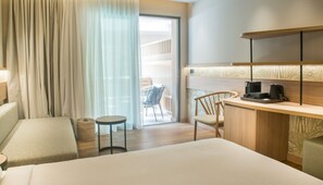 A hotel room with a bed, a desk with a chair, a small round table, and a balcony with a chair. - Senseana Seaside Resort And Aquadventure (Analipsis)