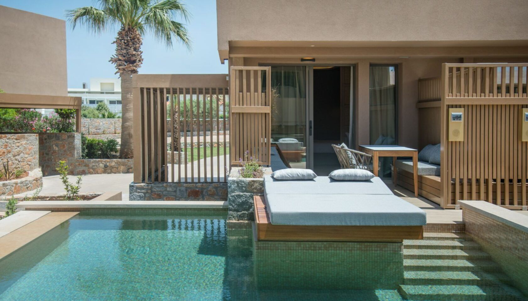 A poolside bedroom with a bed, a small table, and a chair.