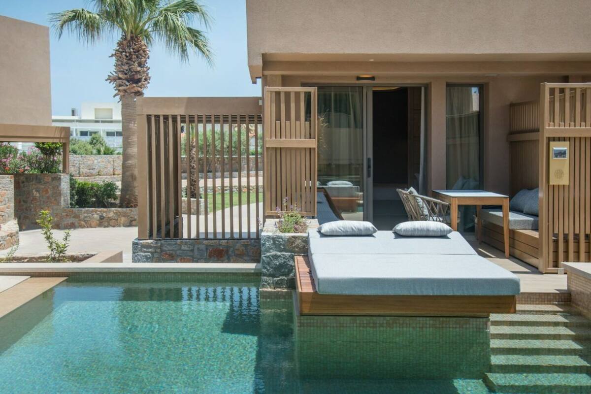 A poolside bedroom with a bed, a small table, and a chair.