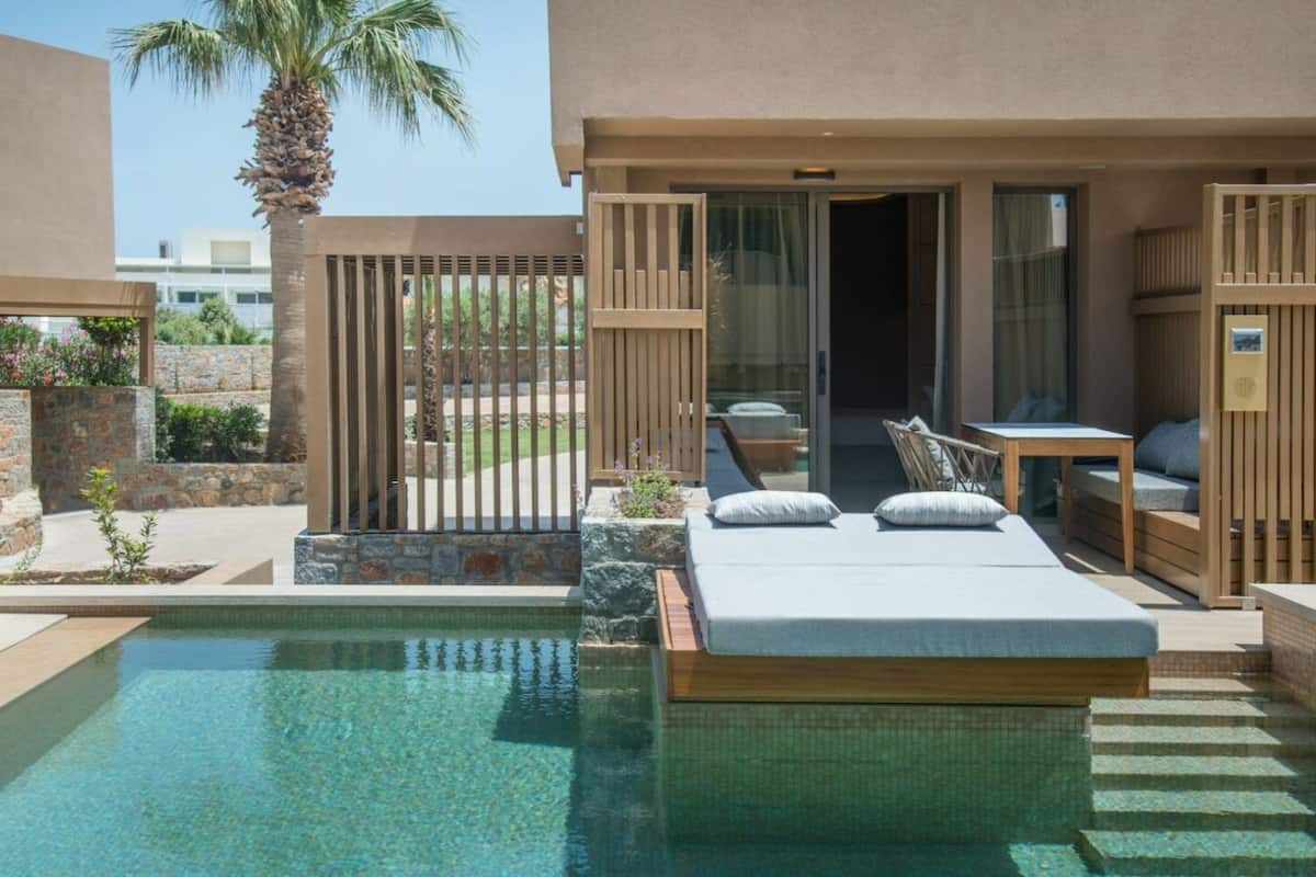 A poolside bedroom with a bed, a small table, and a chair.